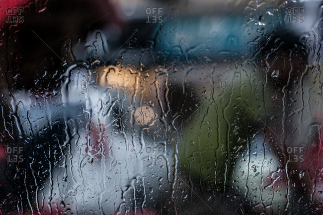Rain soaked window silhouettes a tuk-tuk driver in New Delhi