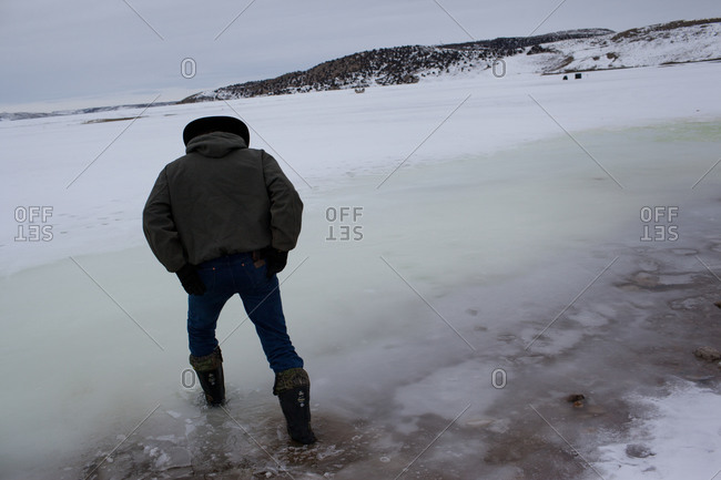 A cowboy tests the ice on a frozen lake in Wyoming