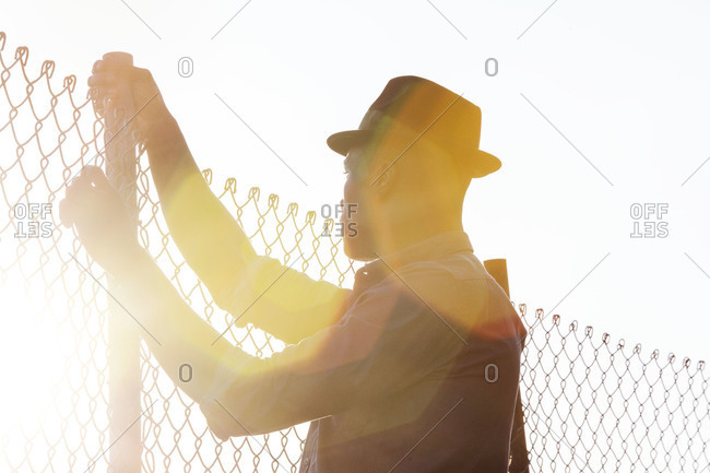 Silhouette of African American man tries to jump over wire fence
