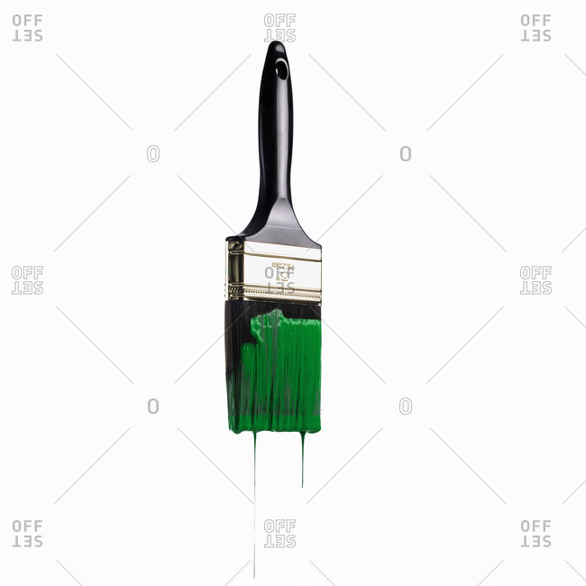 A paintbrush loaded with green paint dripping off the bristles