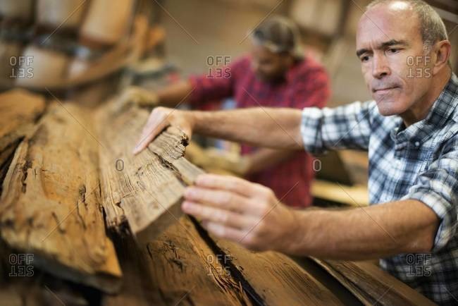 Man measuring and checking planks of wood for re-use and recycling