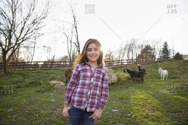 Young girl in the goat paddock enclosure at an animal sanctuary