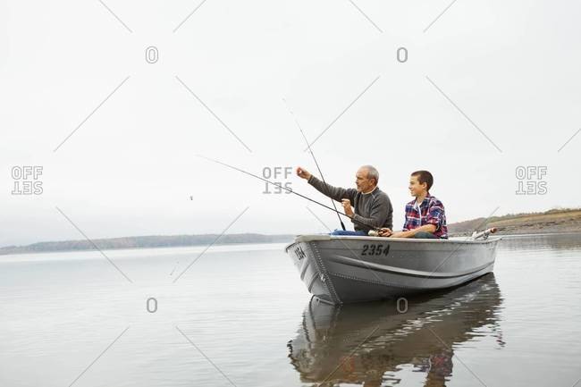 A man and a teenage boy fishing from a boat