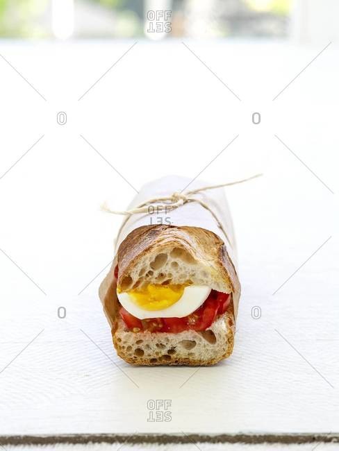 Boiled egg and tomato sandwich in French baguette, wrapped in wax paper