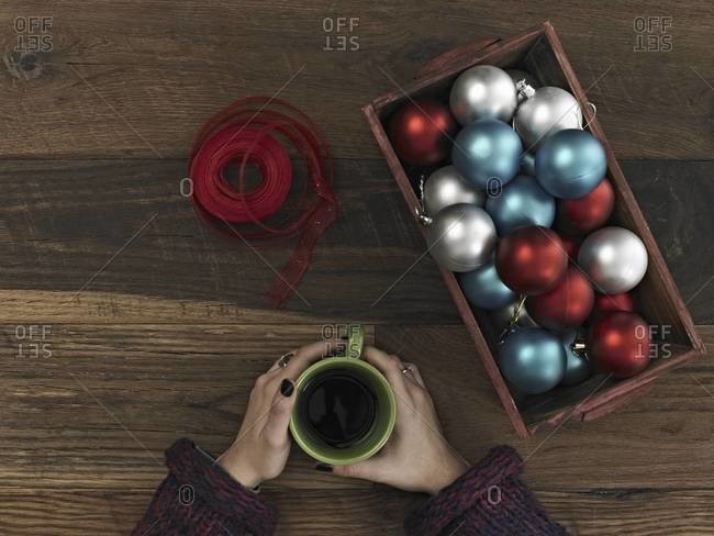 A collection of blue, red and silver ornaments and red ribbon in a box on a wooden board