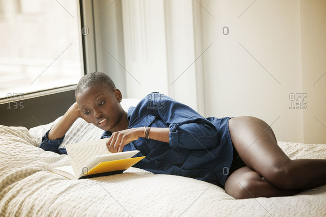 Woman turning the page of a book in bed
