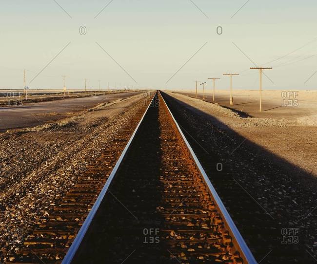 Railroad tracks extending across the flat Utah desert landscape, at dusk.