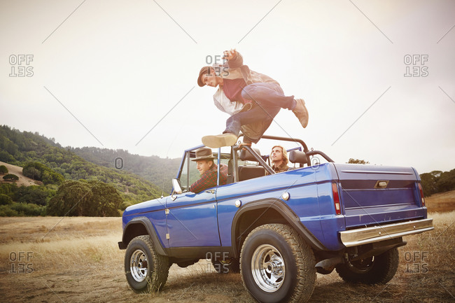 Man jumping from truck in rural landscape