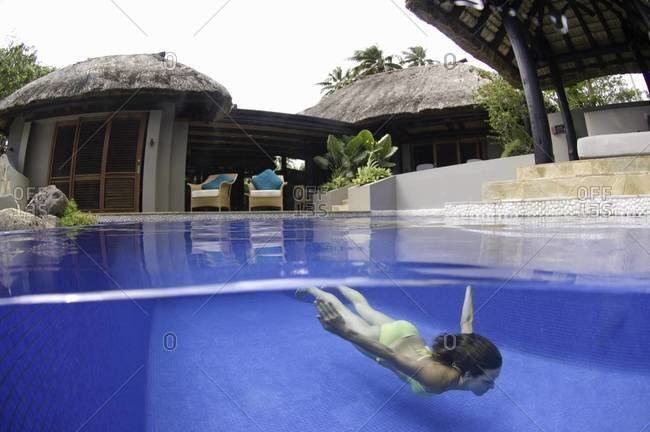 Woman swimming in pool in tropical resort, underwater view, Fiji