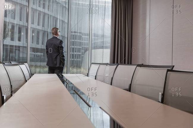 Poland, Warzawa, businessman looking  out of window in conference room at hotel