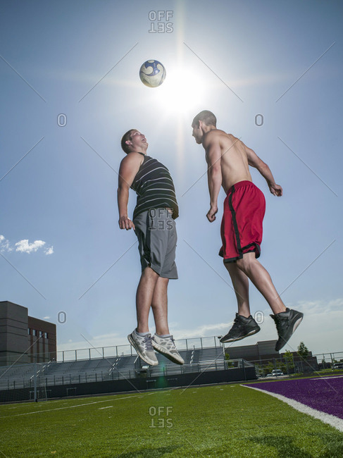 Two young men with soccer ball on sports field