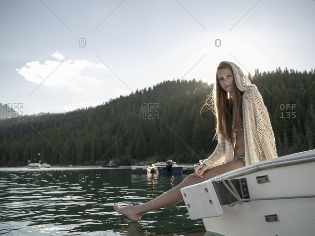 Young woman on boat at mountain lake feet in water