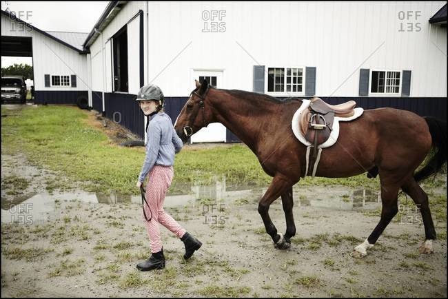 Teenager leading a horse at a barn