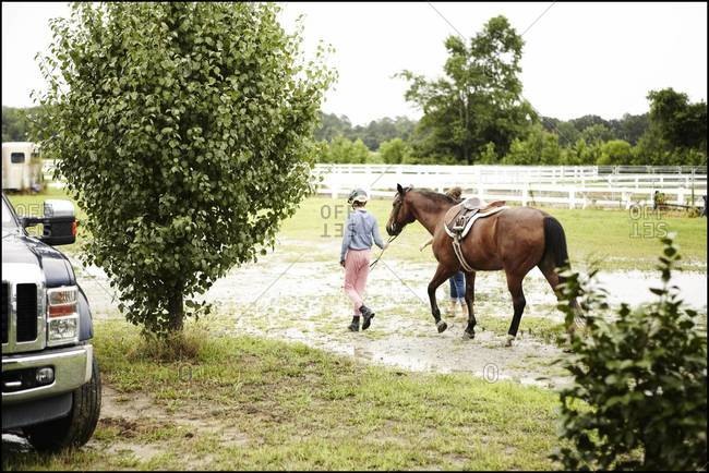 Teenager leading a horse to a pen