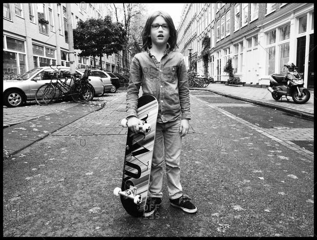 Young boy posing with skateboard on the street