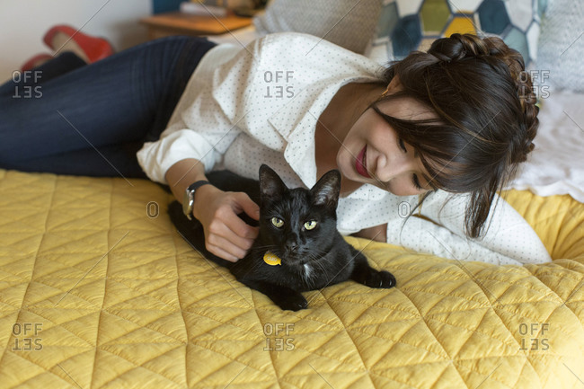 Black cat and woman on bed in bedroom