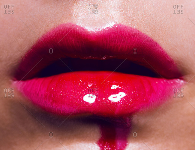 Close up of lip gloss dripping from a woman\'s lips