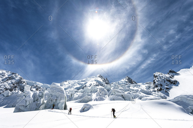 A sun halo above skiers climbing La Jonction, Chamonix, France