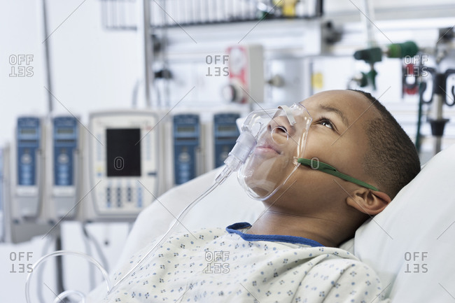 Young wearing oxygen mask in hospital bed