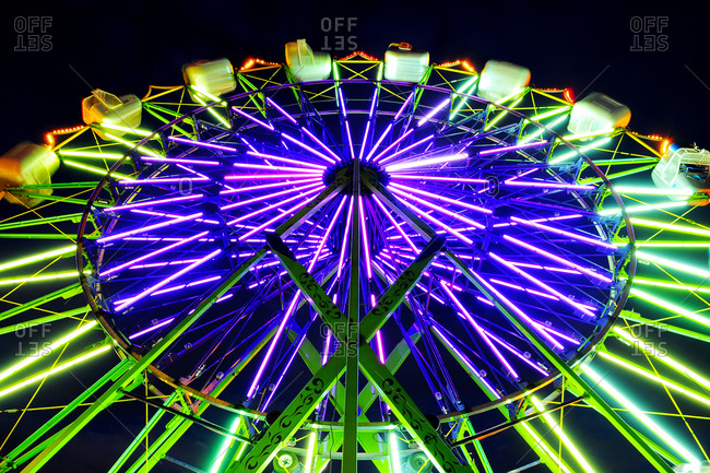 Neon Ferris Wheel ride at amusement park at night