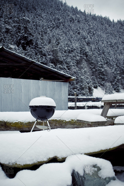 Snow-covered barbecue grill and picnic bench
