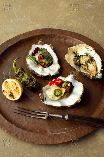 Top view of grilled Pacific oyster presented with lemon and jalapeno