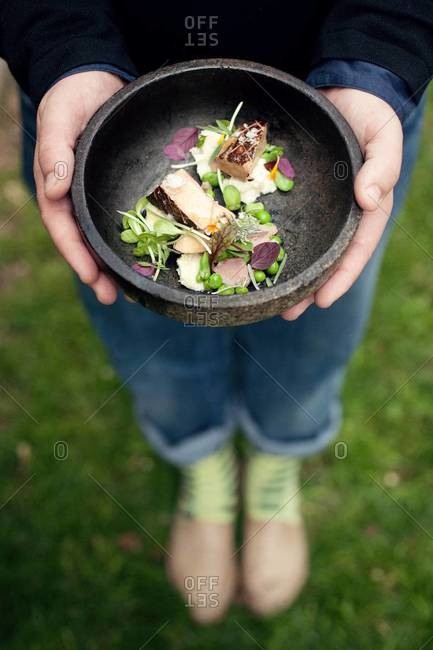 Person holding a dish of foie gras and pea tendrils