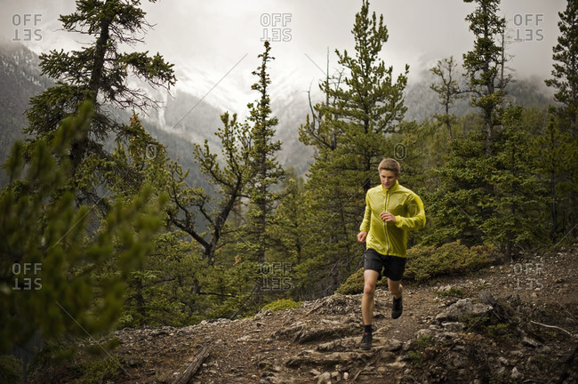 Athletic young man runs on a mountain trail