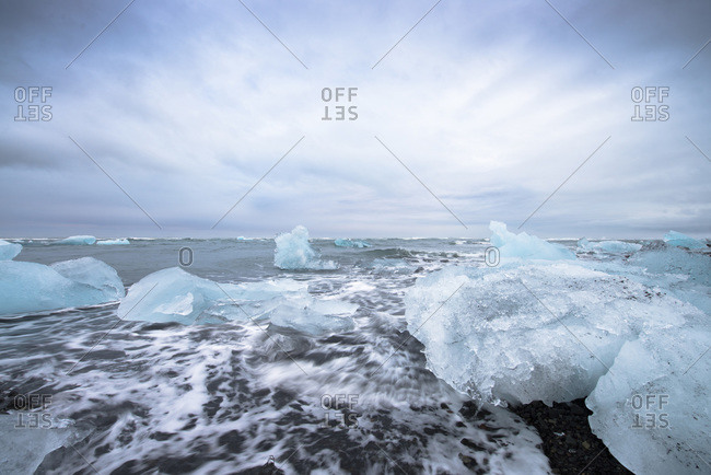 View of the glacial lagoon, landscape with blue iceberg, foaming sea and cloudy blue sky, Jokulsarlon, Skaftafell, Iceland