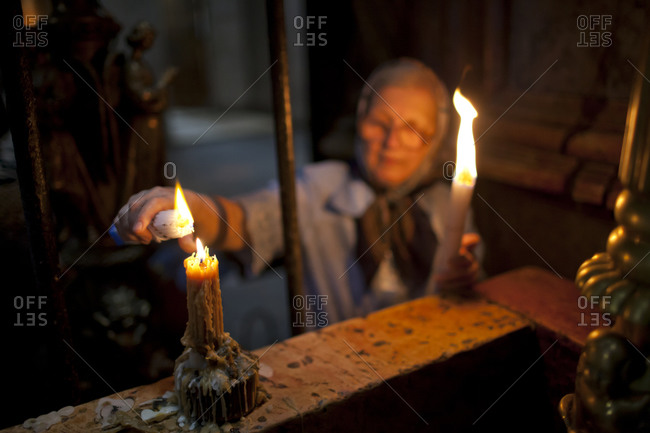 Orthodox Christian woman lights candles at the Church of the Holy Sepulchre