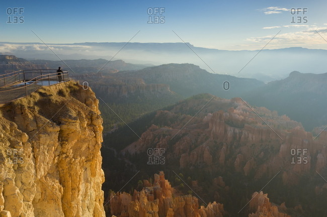 Tourist watching the sunrise with low mist over the sandstone hoodoos in Bryce Amphitheater, Inspiration Point, Bryce Canyon National Park, Utah, United States of America, North America