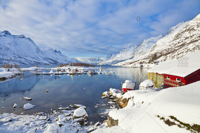 Snow covered mountains, boathouse and moorings in Norwegian fjord village of Ersfjord, Kvaloya island, Troms, Norway, Scandinavia, Europe