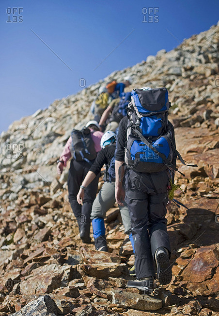 A group nears the summit on a rocky mountain side