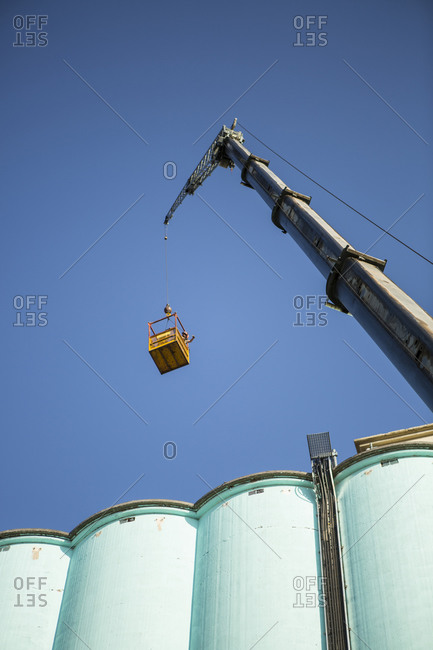 Worker inside of basket hanging from crane