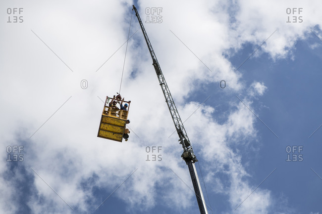 Workers inside basket hanging from crane