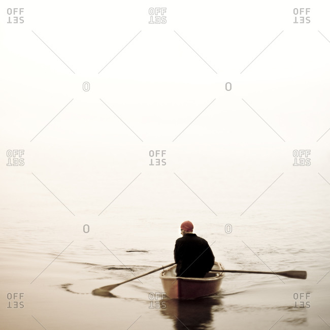 Man in red cap rowing a red rowboat on Lake Sebago near Portland, Maine