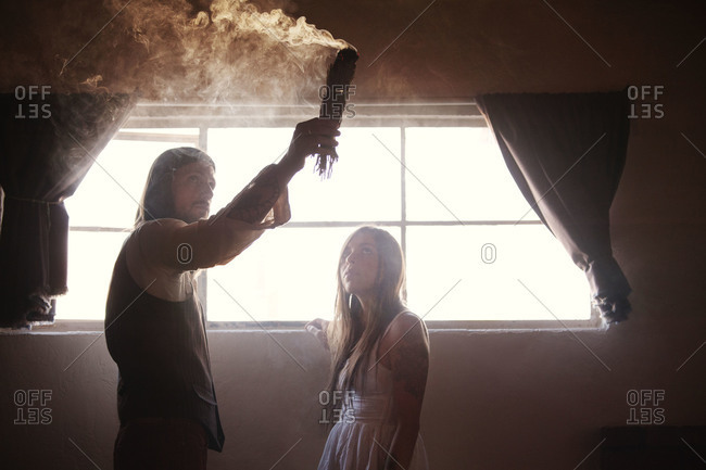 Man and woman burning herbs for cleansing their home