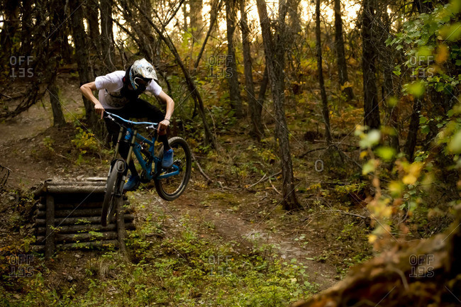 A mountain biker jumps his bike off of a wooden jump amoung fall colors.