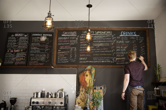 Man writing the menu on a blackboard at a coffee shop