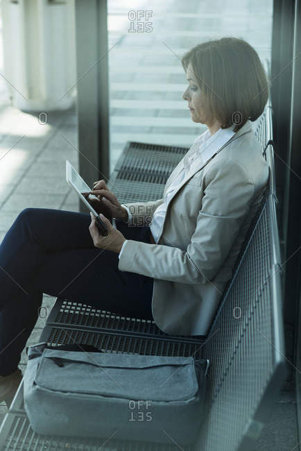 Business woman using tablet computer while waiting on platform
