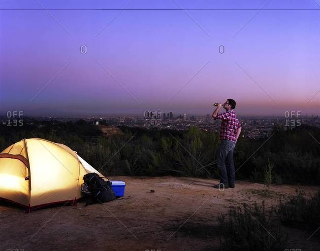 A man drinks beer near a tent