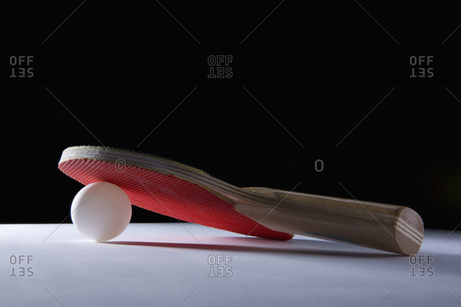 A ping pong racket leaning on a ping pong ball