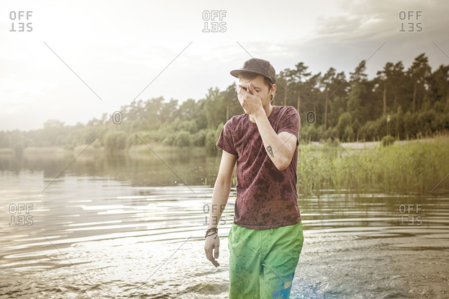 Clothed young man standing in quarry pond
