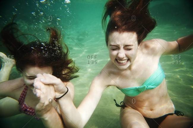 Girls holding hands underwater