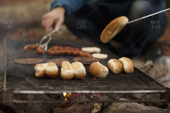 Man preparing hot dogs at campsite