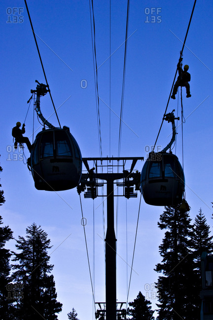 Silhouettes on men fixing a cable car line