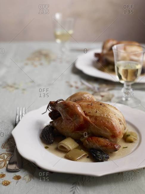 Roasted cornish hens with morels and leeks served on a table