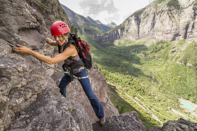 A woman rock climbing in the moutains.