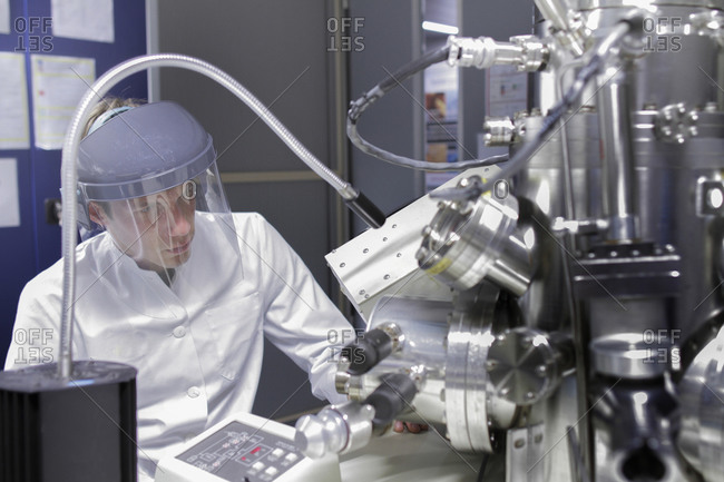 Scientist sitting in analytical laboratory with scanning electron microscope and spectrometer