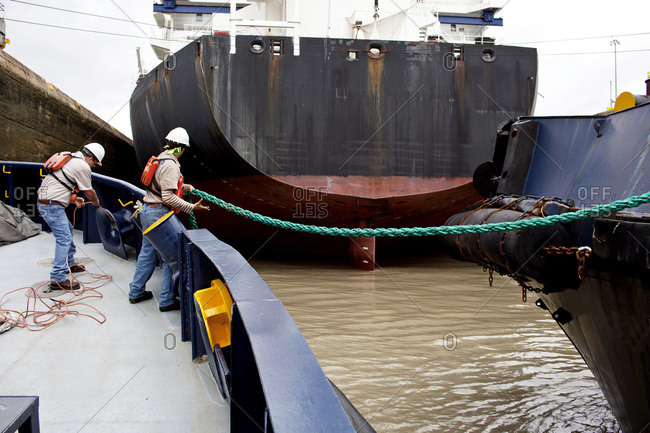 Crew members on a tugboat pull in rope to prepare for the transit through the Miraflores Locks on the Panama Canal